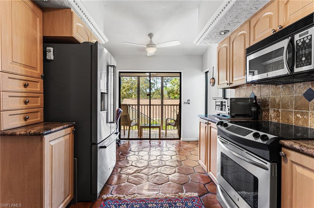 Spacious kitchen features granite counters, tile backsplash, custom cabinets, stainless steel appliances, and a built-in desk area