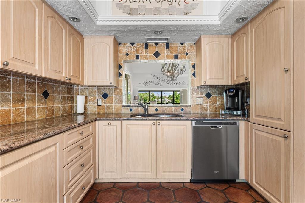 Spacious kitchen features granite counters, tile backsplash, custom cabinets, stainless steel appliances, and a built-in desk area