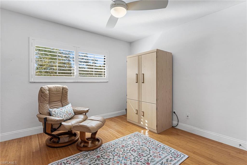 Guest bedroom features wood floors, plantation shutters, and Murphy bed