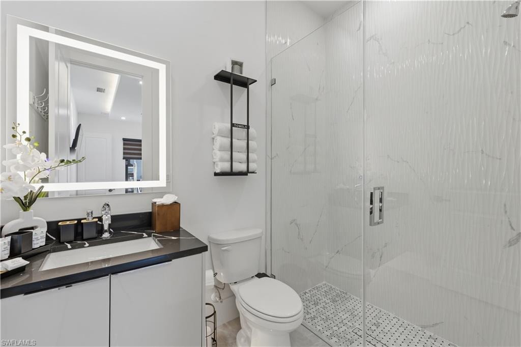 Bathroom featuring vanity and a marble finish shower