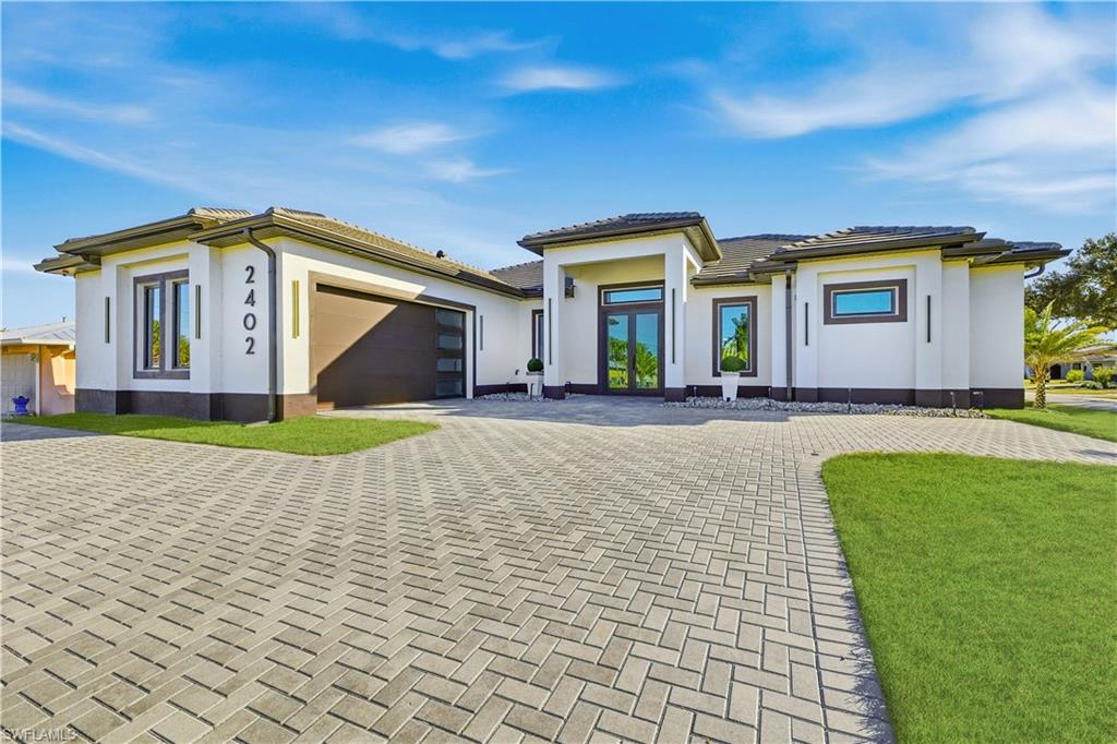 Prairie-style house with decorative driveway, an attached garage, stucco siding, and french doors