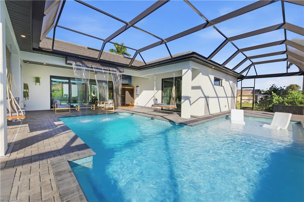 Outdoor pool with a sunroom, glass enclosure, and a patio