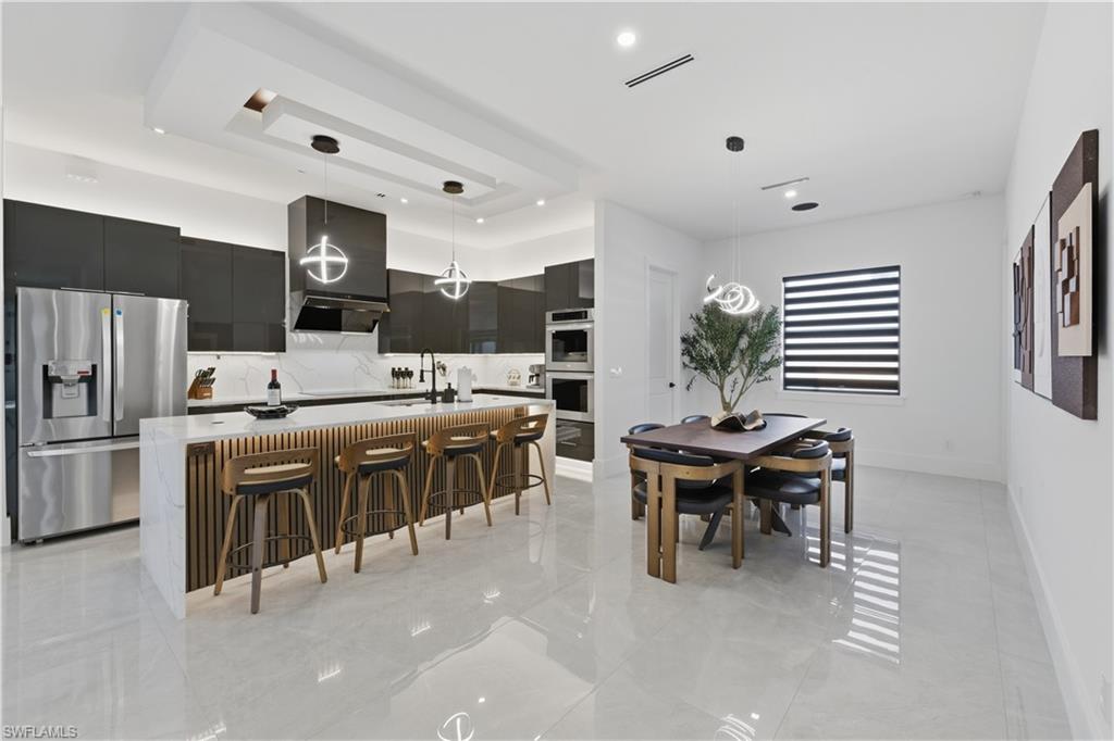 Kitchen featuring a kitchen island with sink, a kitchen breakfast bar, pendant lighting, and modern cabinets