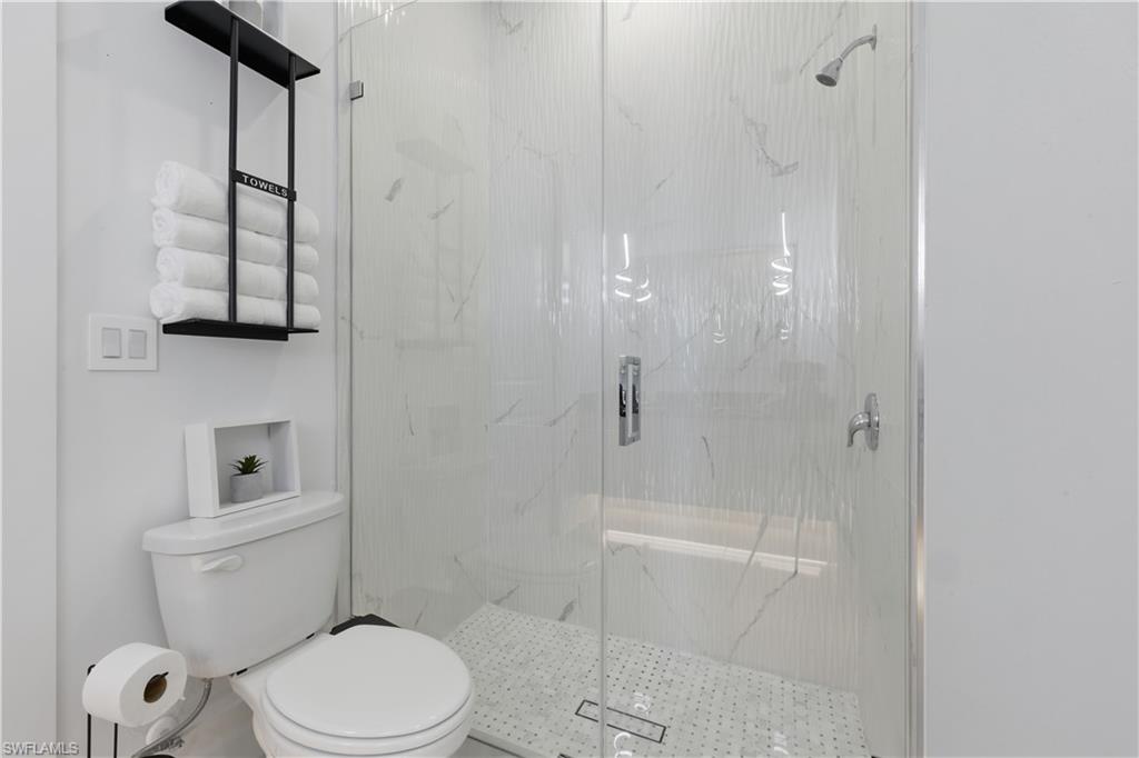 Bathroom featuring toilet and a marble finish shower