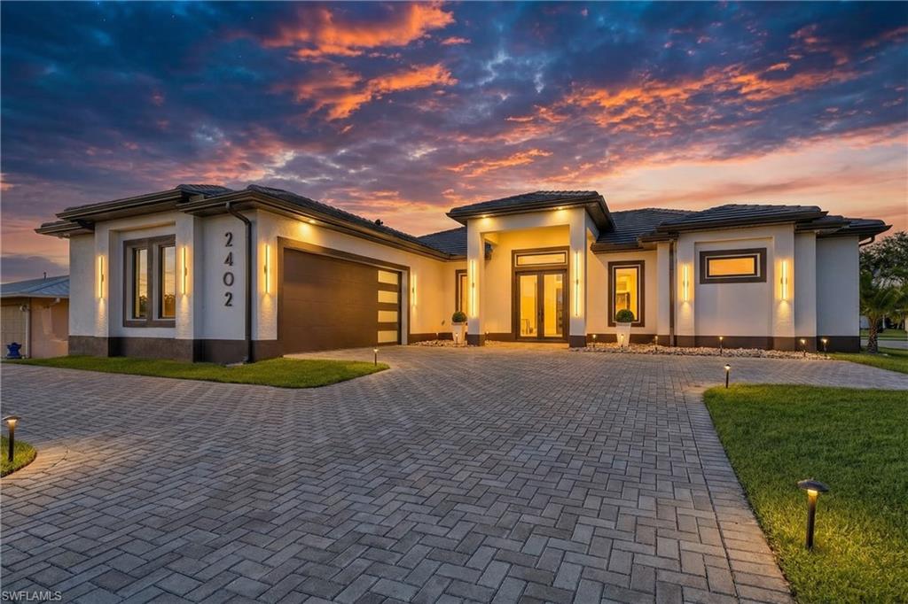 Prairie-style home with a garage, decorative driveway, and stucco siding
