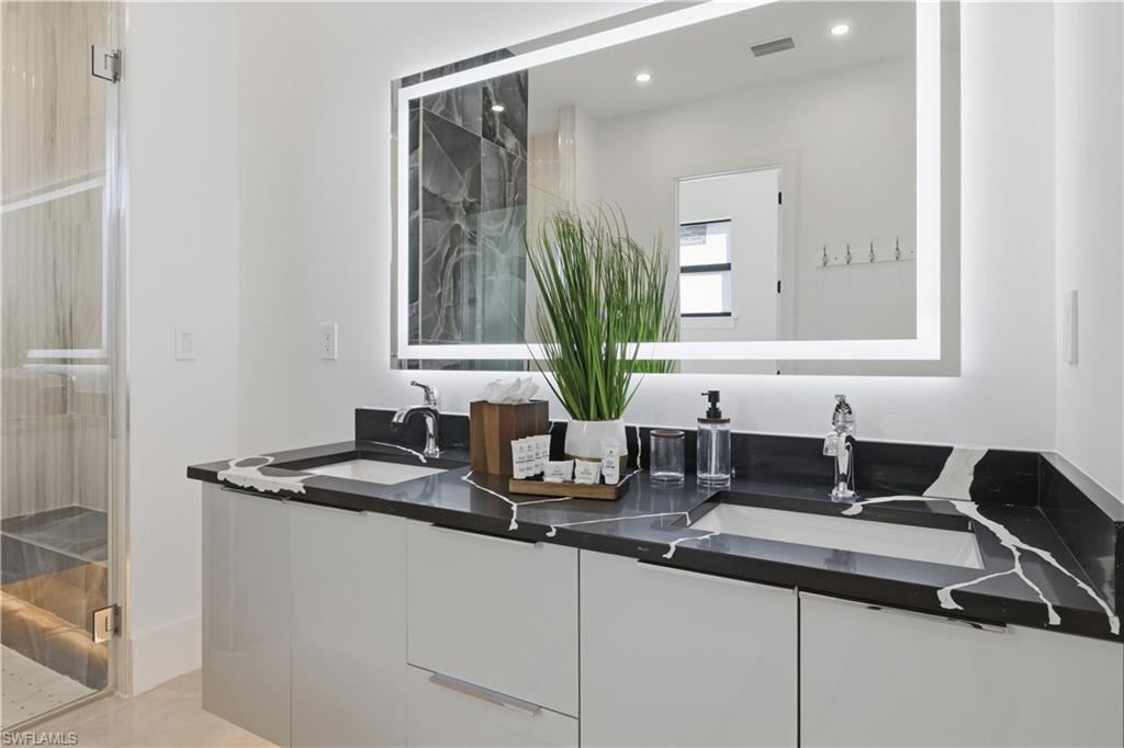 Bathroom with double vanity, a marble finish shower, recessed lighting, and light tile patterned floors