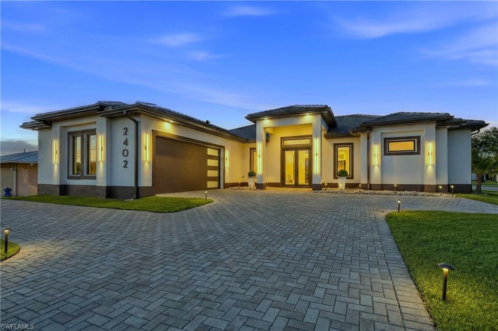 Prairie-style home featuring a garage, decorative driveway, and stucco siding