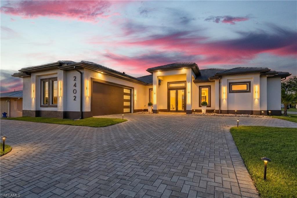 Prairie-style house featuring a garage, decorative driveway, and stucco siding