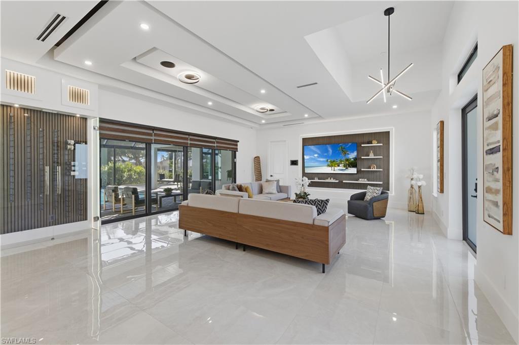 Living room featuring a tray ceiling and suspended lighting