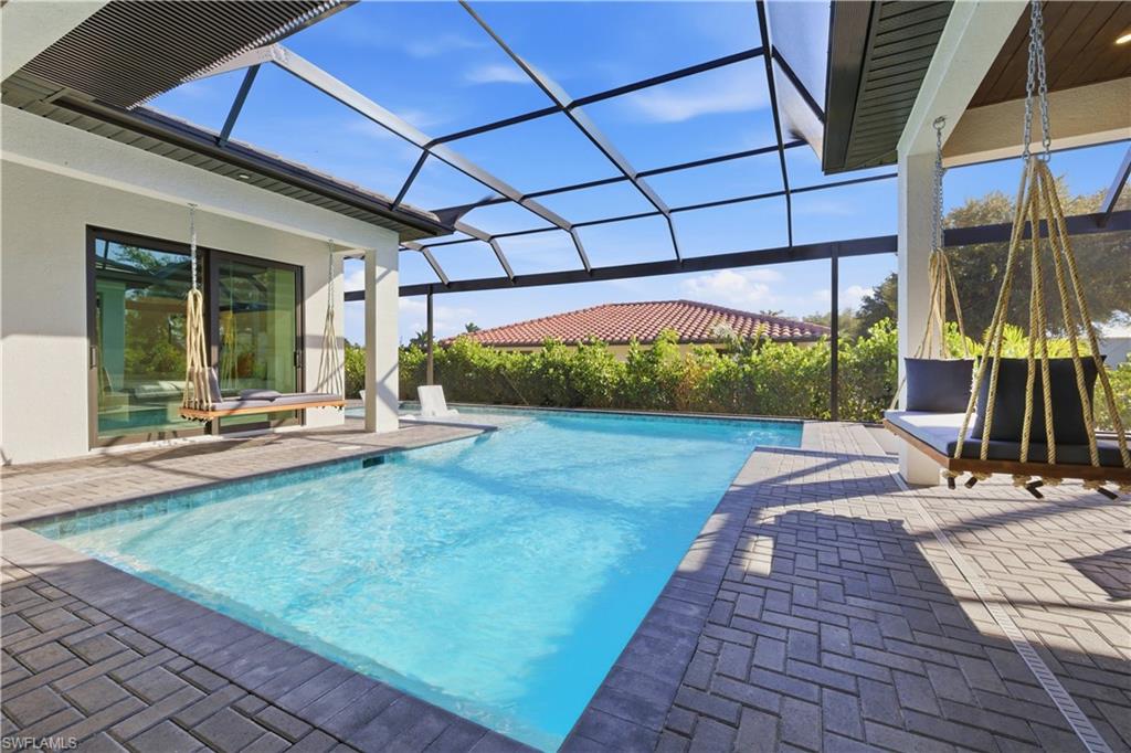 Outdoor pool featuring a sunroom, a patio, and glass enclosure