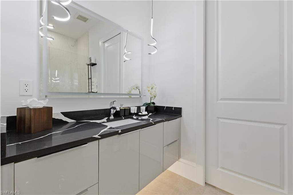 Full bath featuring vanity, light tile patterned floors, and a shower