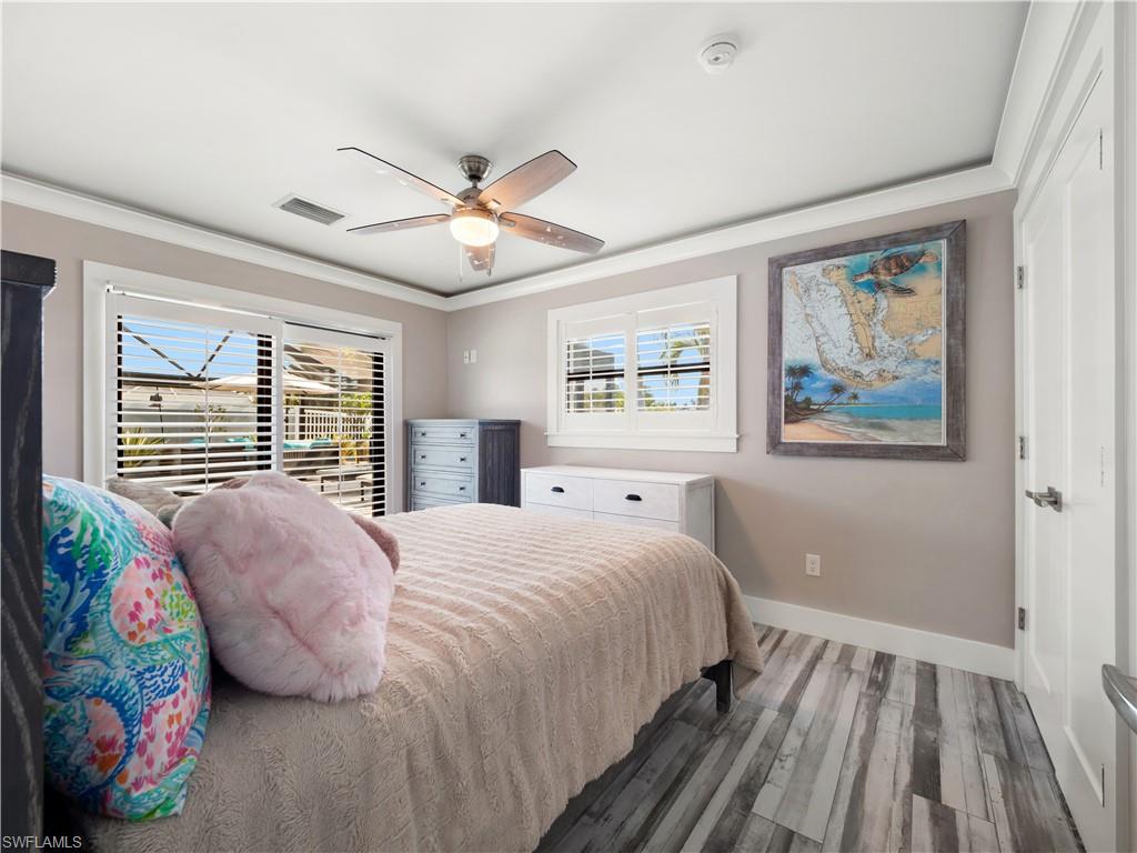 Bedroom with wood finished floors, ornamental molding, and a ceiling fan