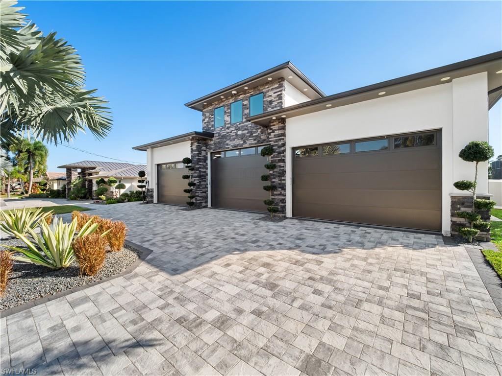 View of front facade with stone siding, stucco siding, and decorative driveway