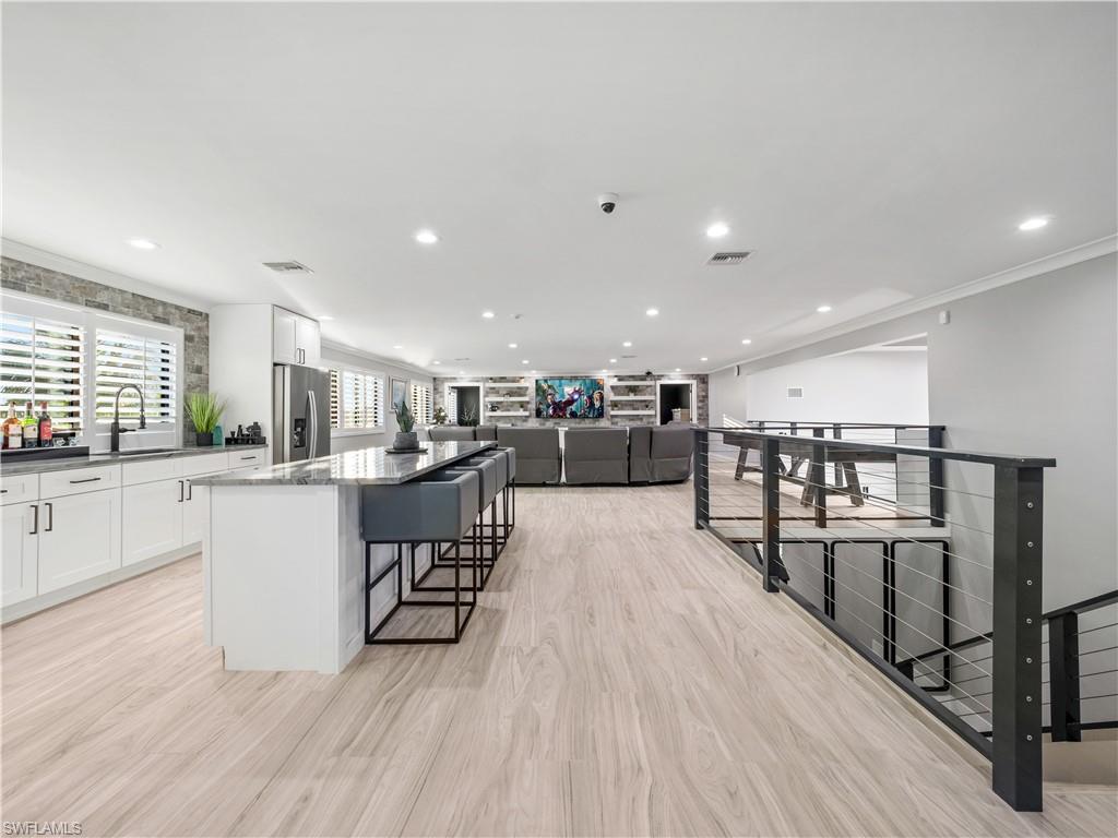 Kitchen featuring open floor plan, a center island, a breakfast bar area, dark stone counters, and recessed lighting
