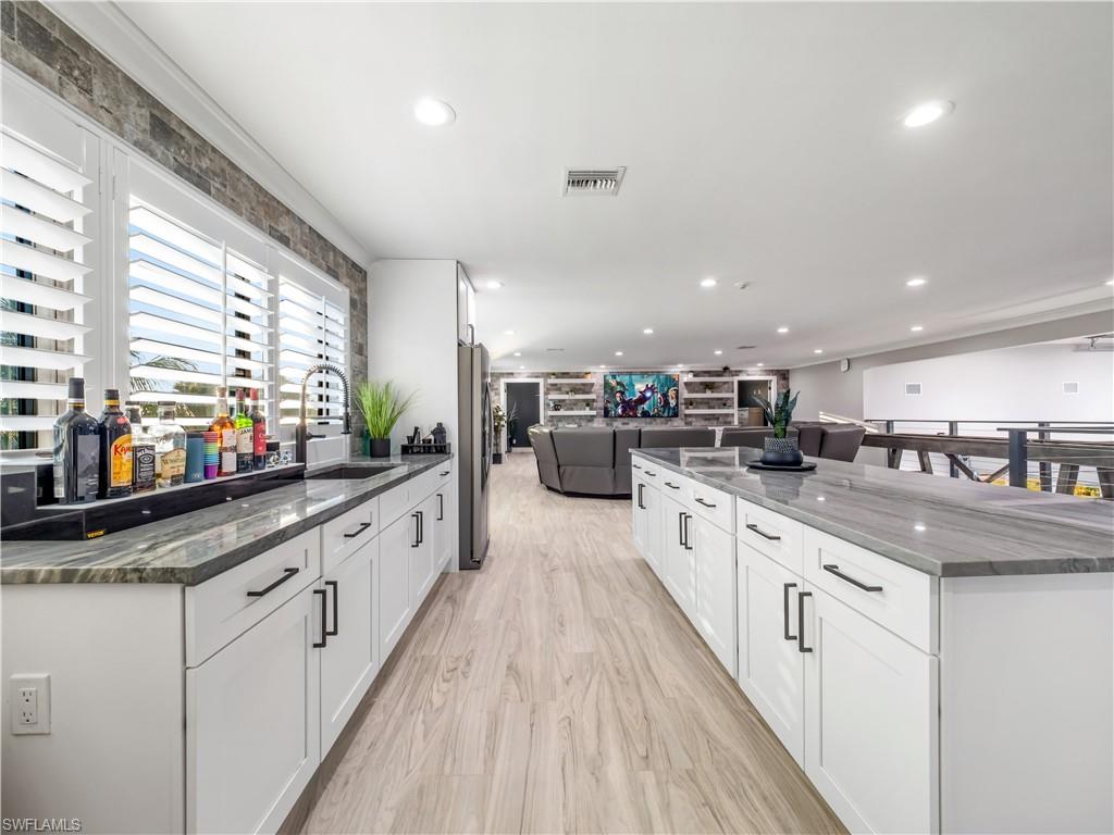 Kitchen with open floor plan, dark stone countertops, white cabinetry, a large island, and light wood-style floors