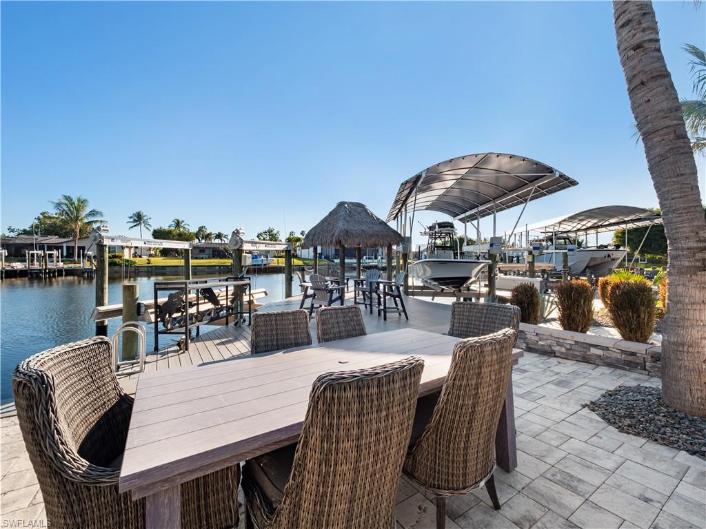 View of patio / terrace featuring boat lift, a boat dock, a water view, and outdoor dining area