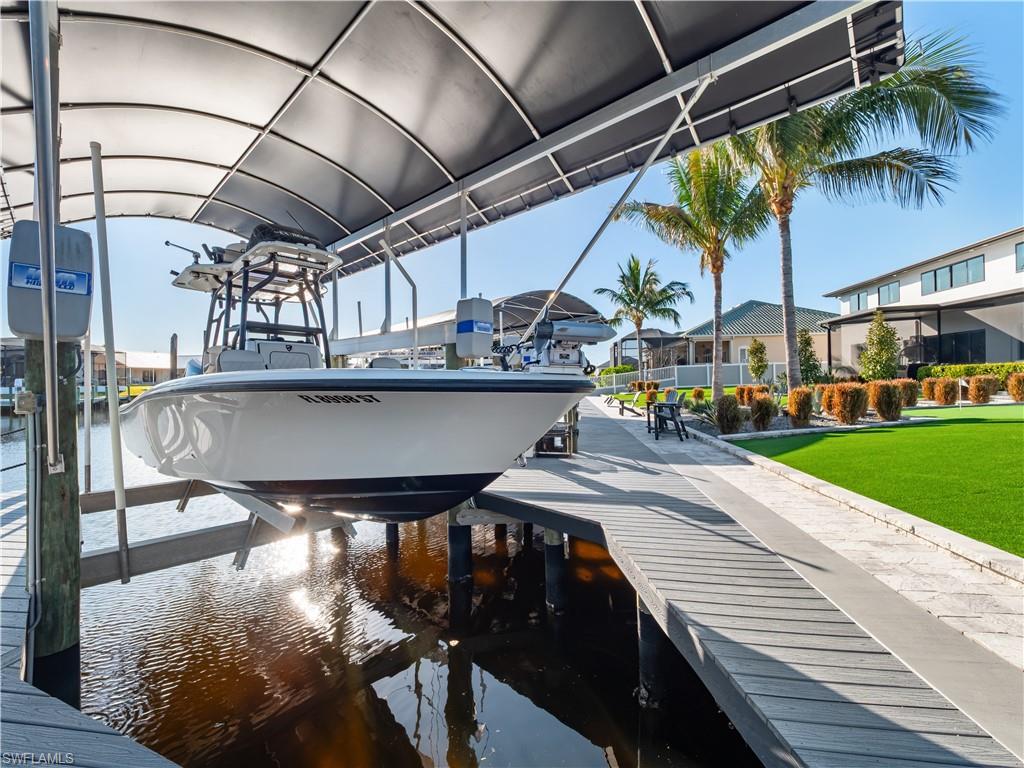 Dock area featuring boat lift, a water view, and a yard