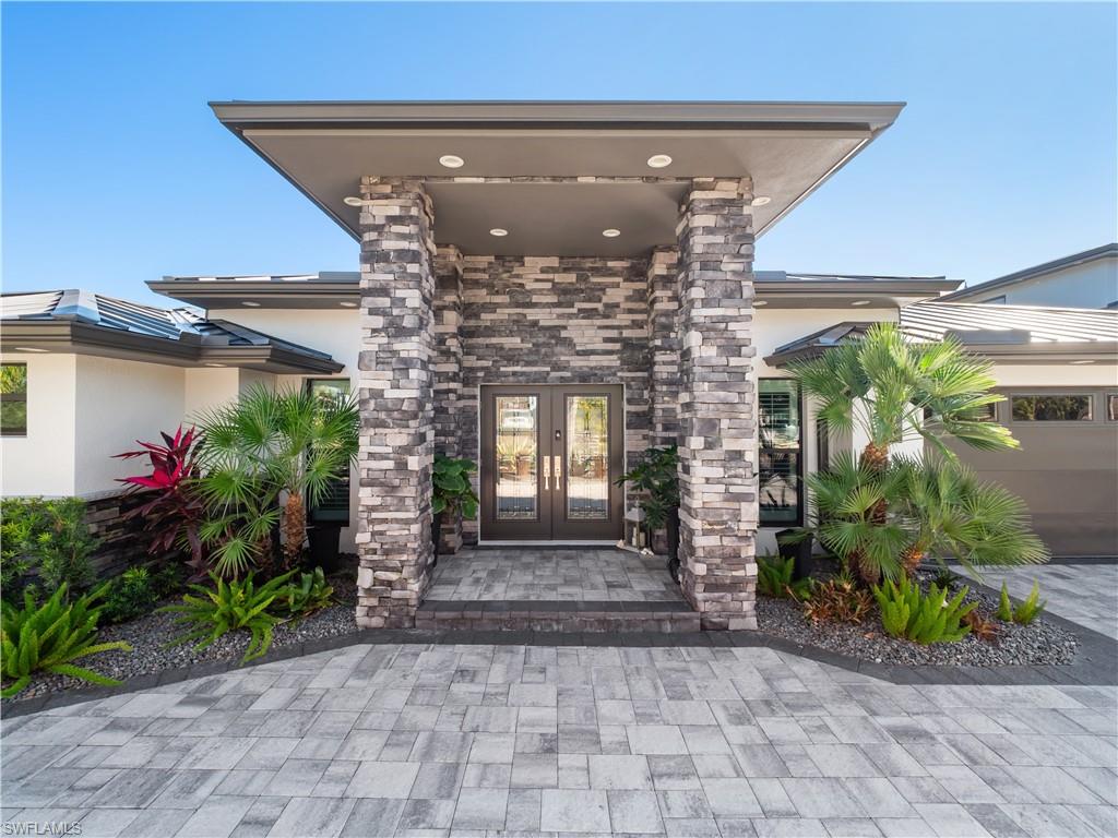 Doorway to property featuring french doors, stucco siding, and stone siding