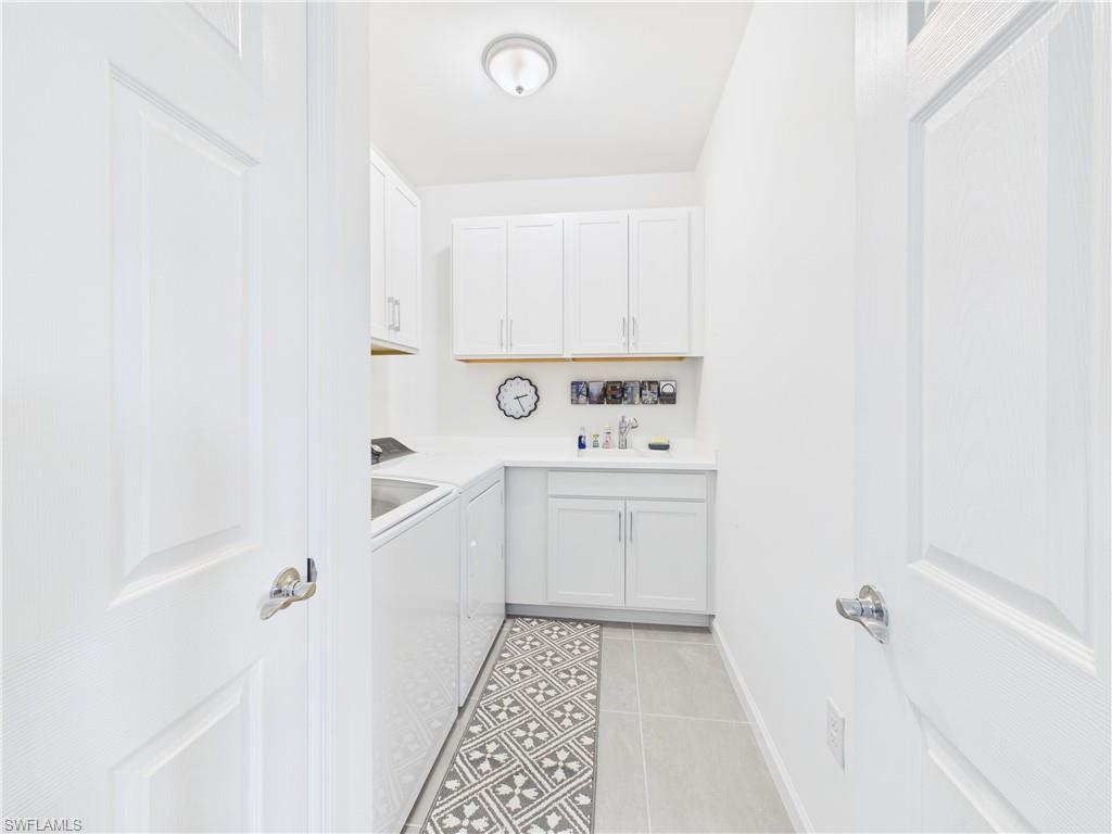 Laundry area featuring light tile patterned flooring, washer and clothes dryer, and cabinet space
