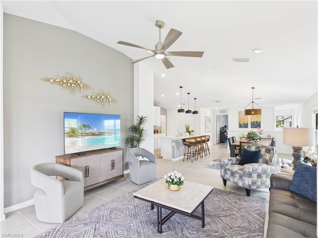 Living room featuring a ceiling fan, vaulted ceiling, and light tile patterned flooring