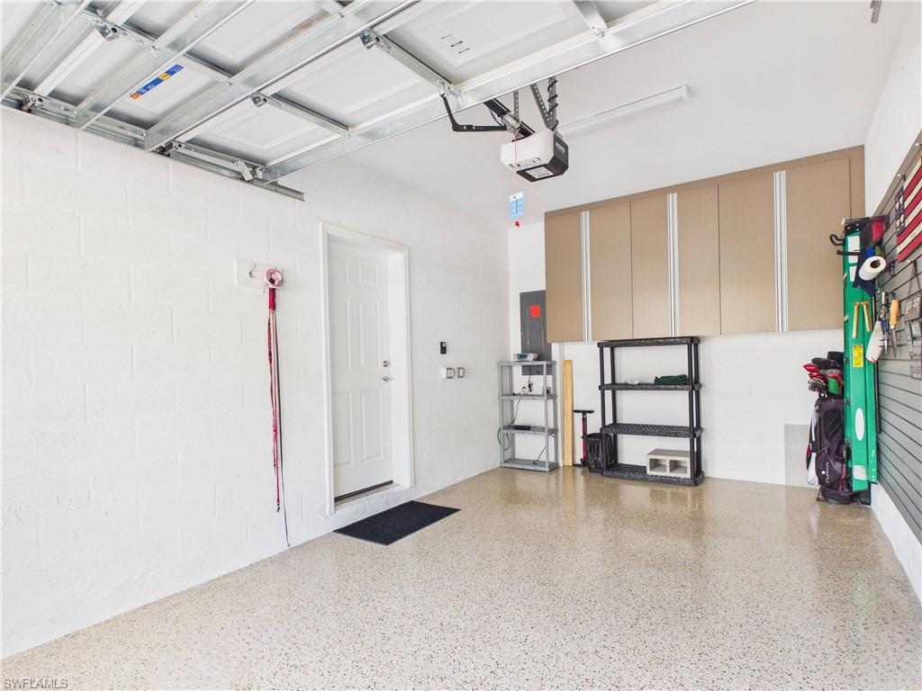 Garage with concrete block wall, electric panel, and a garage door opener