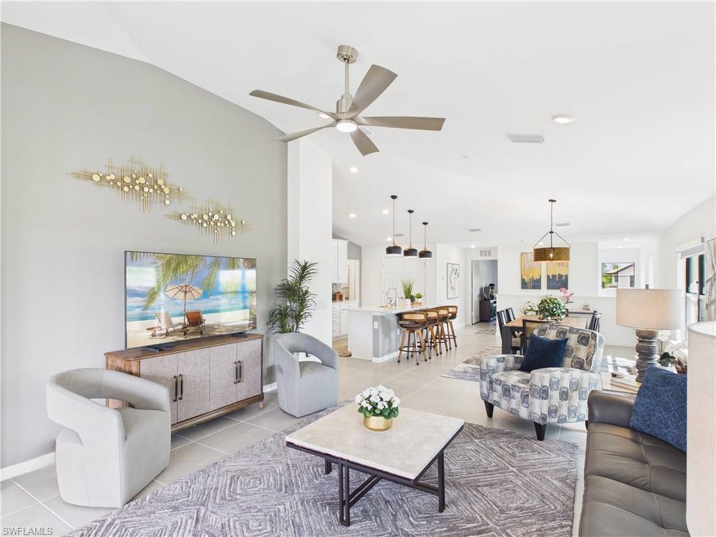 Living room featuring light tile patterned floors, ceiling fan, and vaulted ceiling