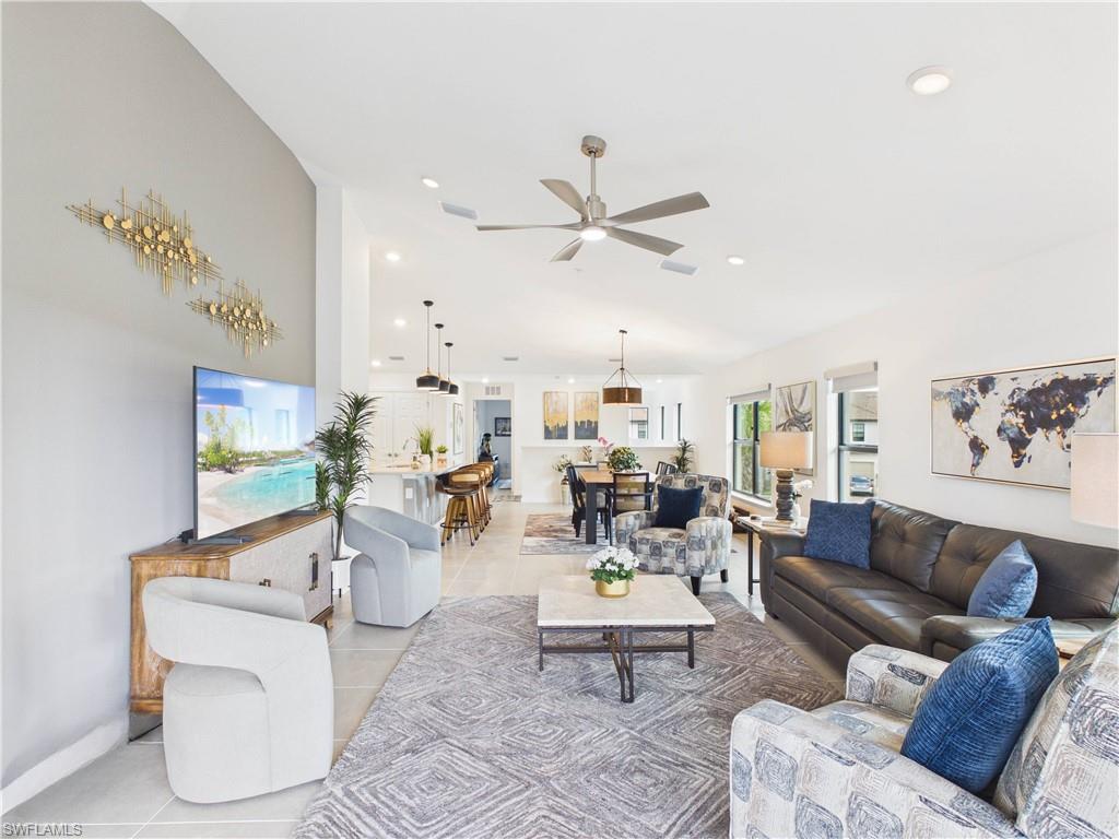 Living room featuring ceiling fan, light tile patterned floors, recessed lighting, and vaulted ceiling