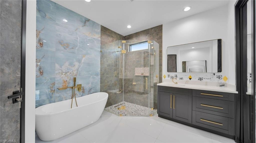 Full bath featuring vanity, a shower stall, a freestanding tub, recessed lighting, and light tile patterned floors