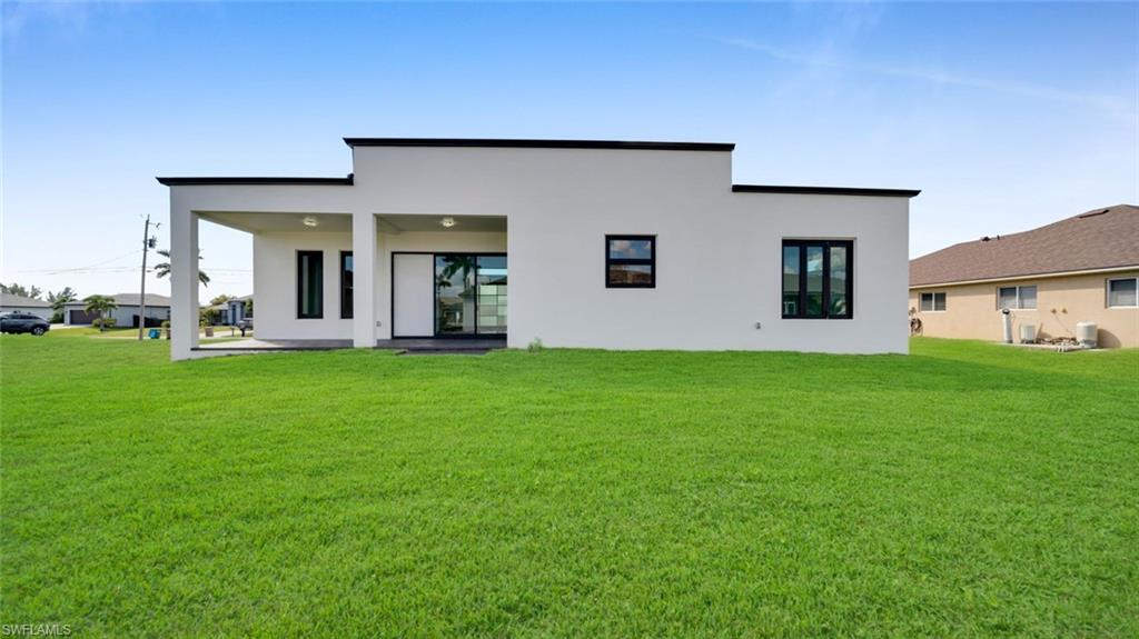 Back of property featuring a yard, a patio, and stucco siding