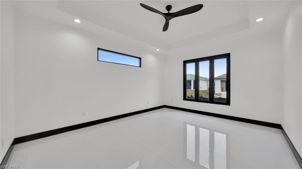 Unfurnished room featuring recessed lighting, tile patterned floors, ceiling fan, and a tray ceiling