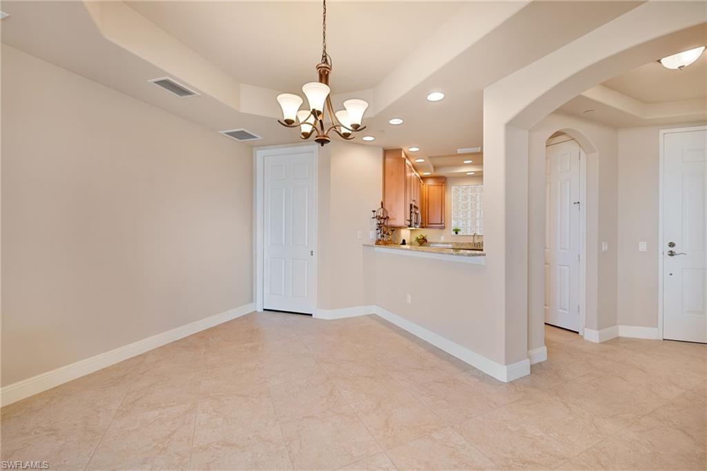 Unfurnished dining area with a raised ceiling, a chandelier, and arched walkways