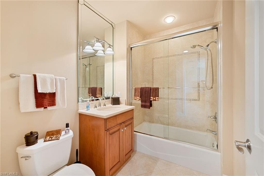 Full guest bath featuring vanity, light tile patterned flooring, and bath / shower combo with glass door