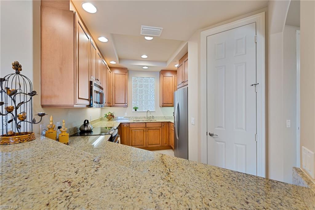 Kitchen with light stone counters, stainless steel appliances, and recessed lighting