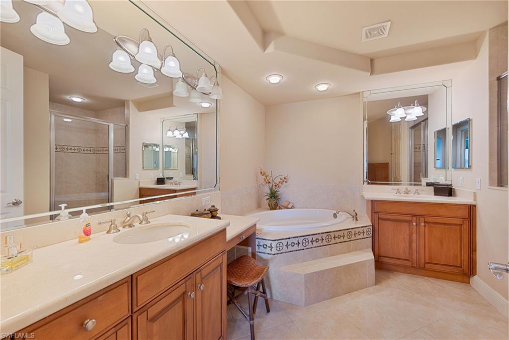 Ensuite with a stall shower, two vanities, light tile patterned floors, and a garden tub