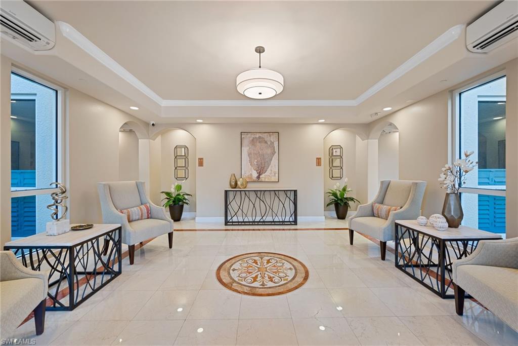 Lobby featuring a raised ceiling, ornamental molding, arched walkways, and recessed lighting