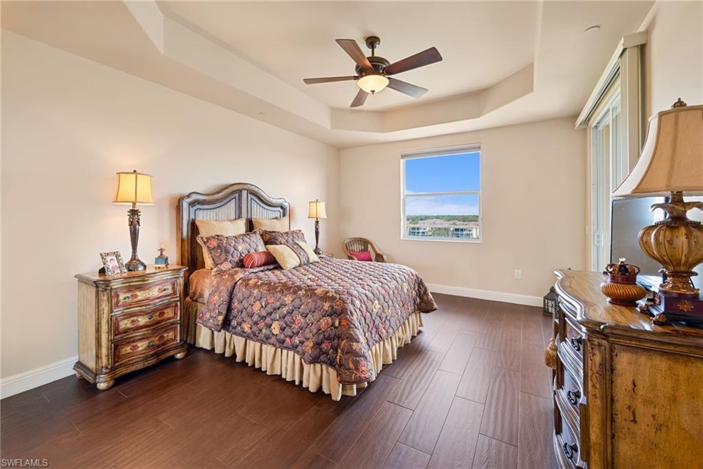 Bedroom featuring a ceiling fan, a raised ceiling, and dark wood finished floors
