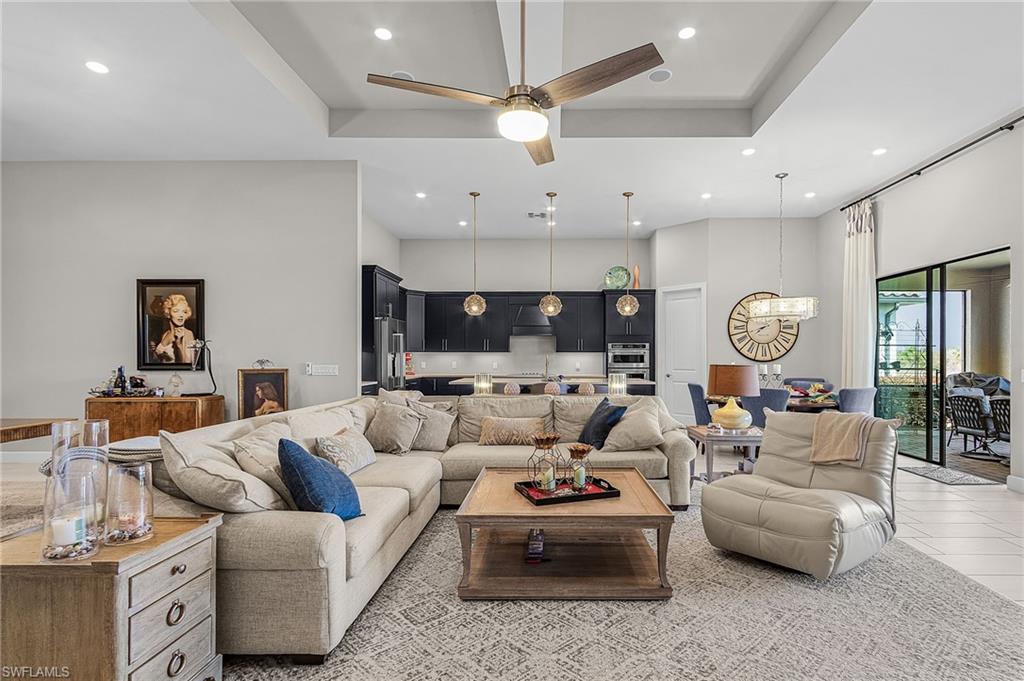 Living room featuring a ceiling fan, a high tray ceiling, and a chandelier