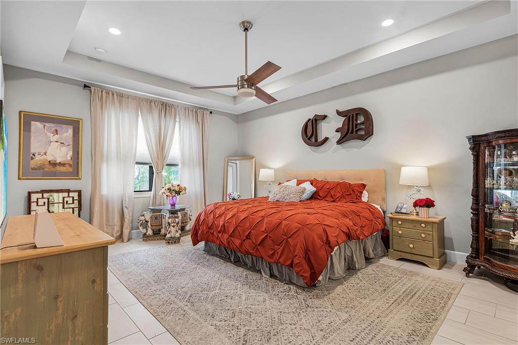 Bedroom with a raised ceiling, ceiling fan, and recessed lighting