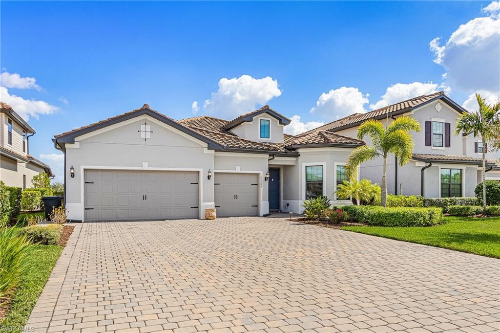 Mediterranean / spanish-style home with a tiled roof, stucco siding, decorative driveway, a garage, and a front yard