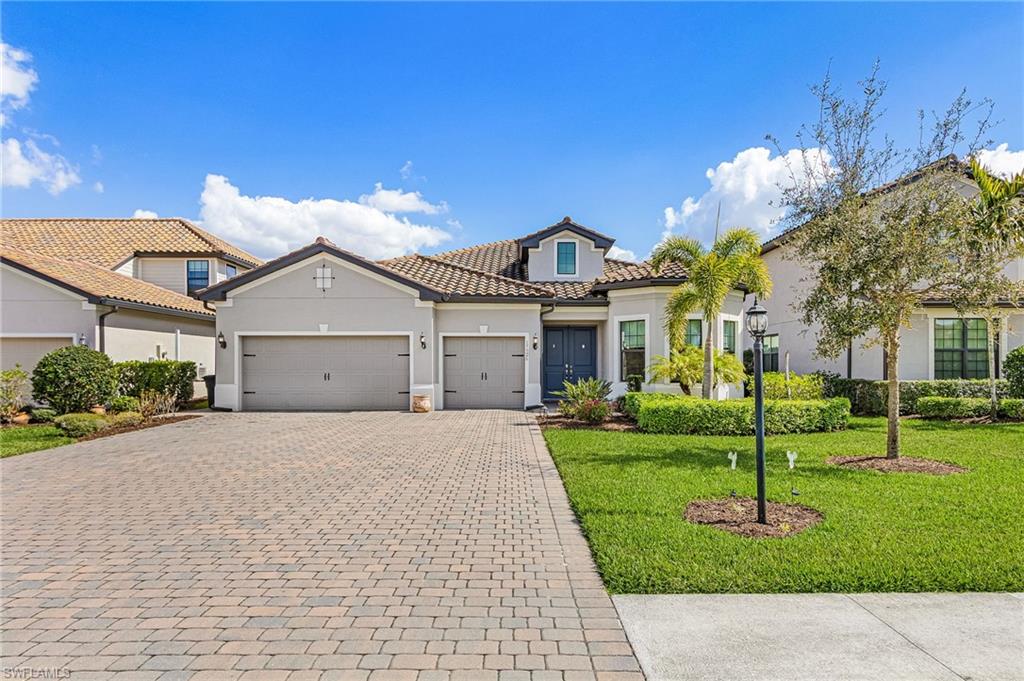 Mediterranean / spanish house featuring stucco siding, decorative driveway, a front yard, a tile roof, and a garage