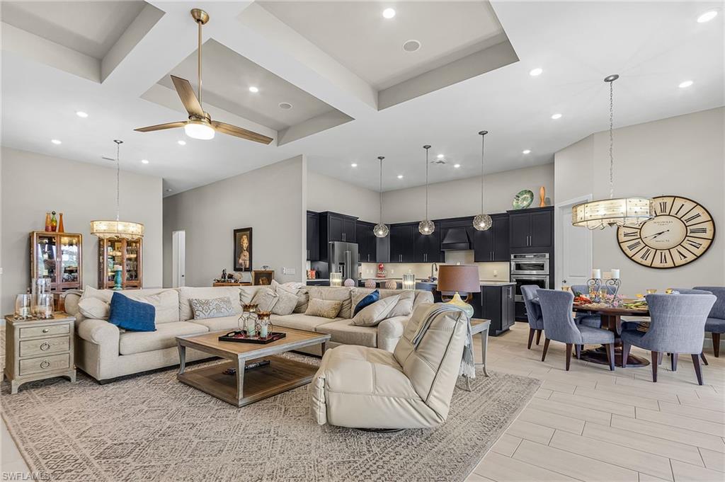 Living room with a chandelier, ceiling fan, coffered ceiling, and wood tiled floors