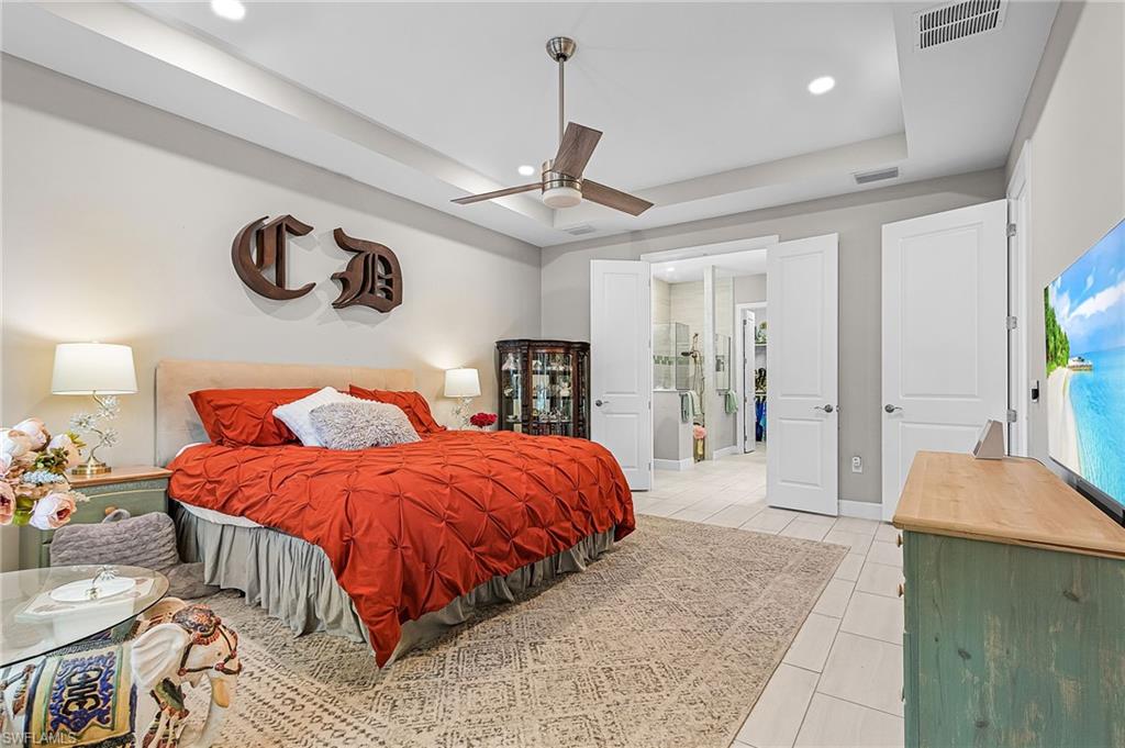 Bedroom with a tray ceiling, light tile patterned floors, recessed lighting, and ceiling fan