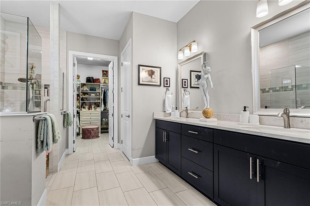 Full bath featuring a stall shower, double vanity, and a walk in closet
