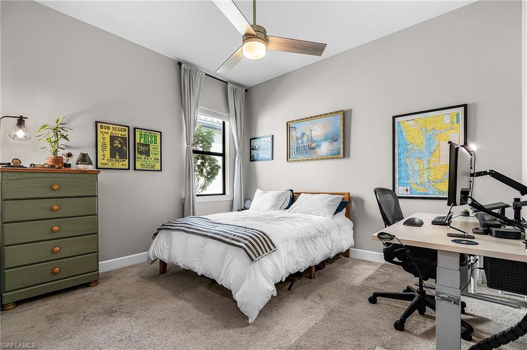 Bedroom featuring an office area, light colored carpet, and a ceiling fan