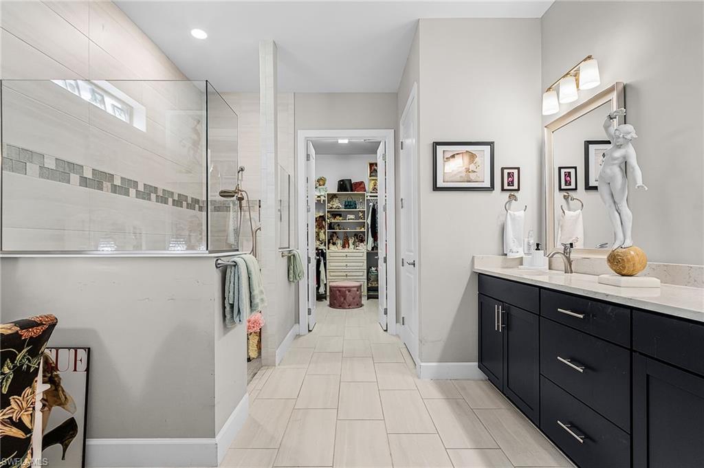 Bathroom featuring walk in shower, vanity, and a walk in closet