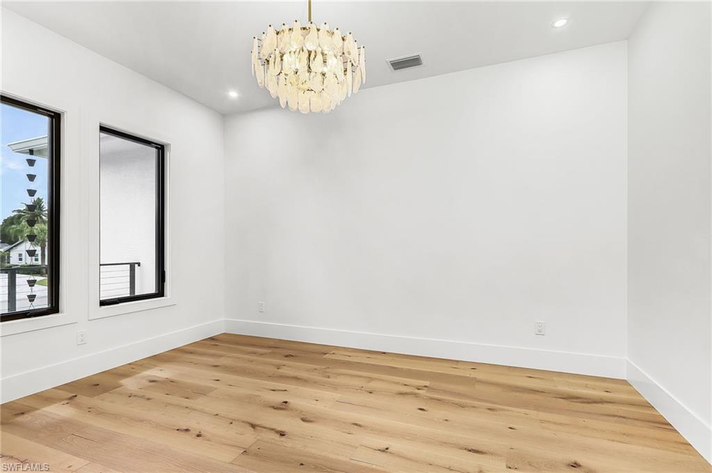 Empty room with hanging lights and light wood finished floors