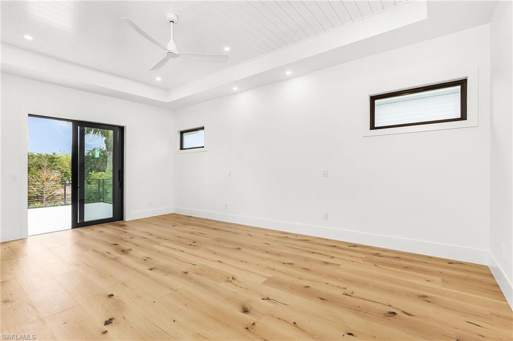 Spare room with light wood-style floors, ceiling fan, recessed lighting, and a wood tray ceiling