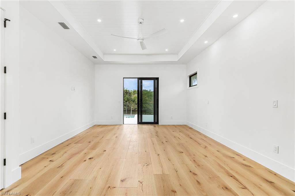 Unfurnished room featuring ceiling fan, light wood-style flooring, recessed lighting, and a raised ceiling