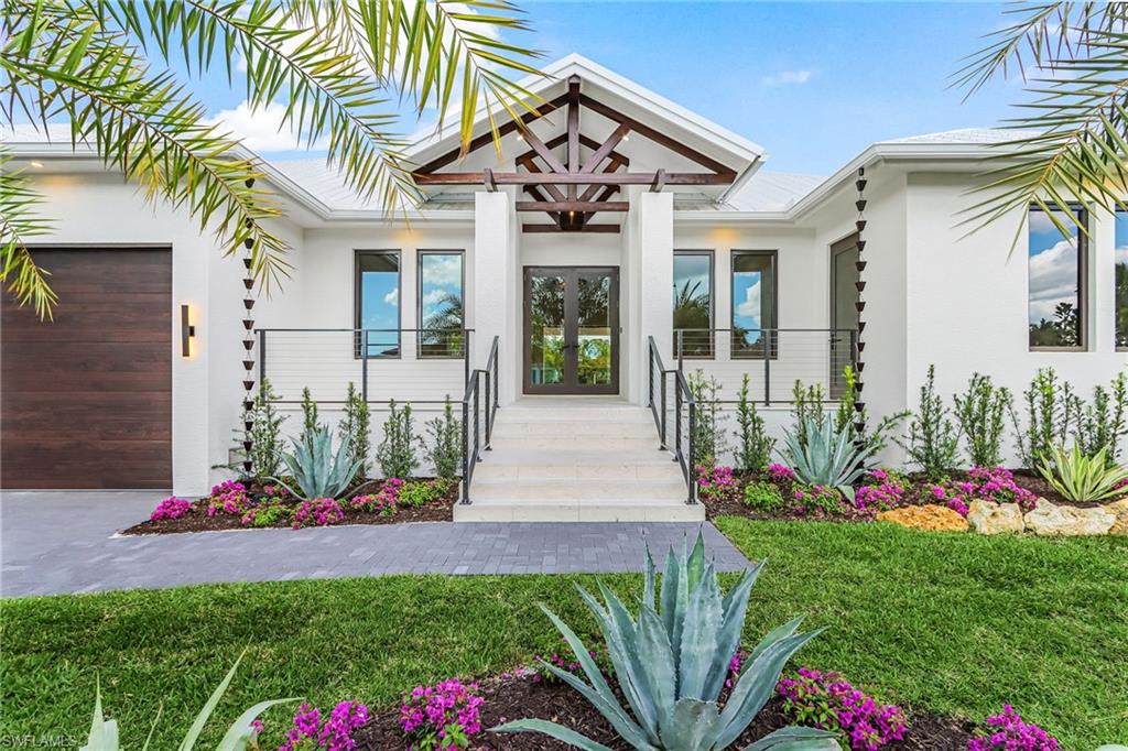 Doorway to property featuring french doors, stucco siding, an attached garage, and a yard