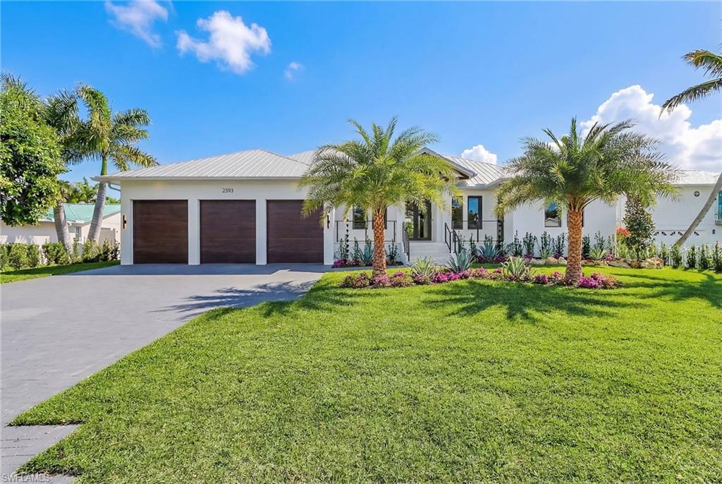 View of front of home with a garage, driveway, and a metal roof